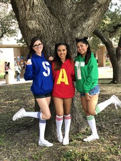 three young women standing next to a tree in front of a large tree with the number four on it