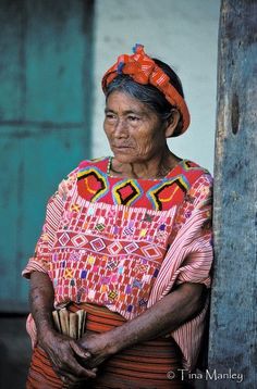 an old woman is standing in front of a door with her hand on her hip