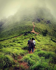 two people are walking up a grassy hill