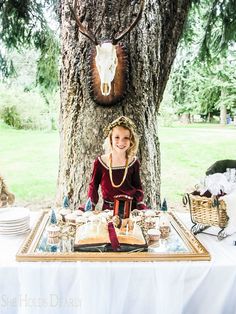 a woman sitting at a table in front of a deer head hanging from a tree