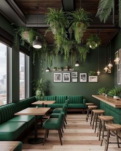 the interior of a restaurant with green booths and plants hanging from the ceiling, along with wooden tables