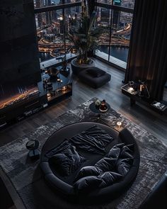 a living room filled with furniture and a large window overlooking the city at night time