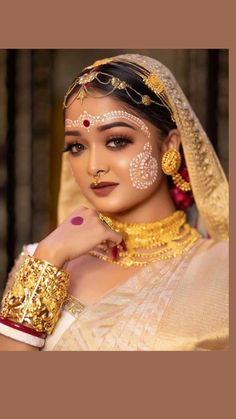 a woman with gold jewelry and makeup on her face is posing for a photo in front of