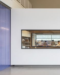 a group of people sitting at a table in front of a window with blue curtains