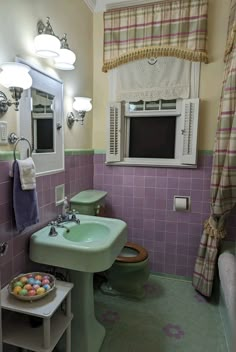 a bathroom with purple and green tiles on the walls, two sinks and a window