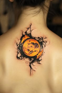 the back of a woman's neck with an orange and black tattoo on it