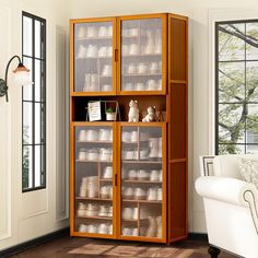 a large wooden cabinet with glass doors in a living room next to a white chair