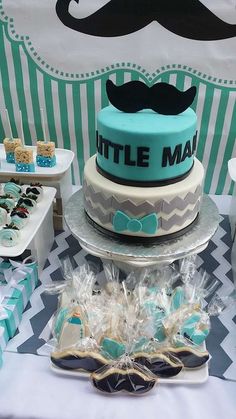 there is a cake and cupcakes on the table at this little man birthday party