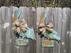 two wooden signs with bows on them sitting next to a fence