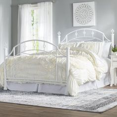 a white bed sitting on top of a wooden floor next to a dresser and window