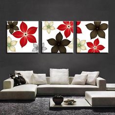 three red and brown flower paintings on a wall above a couch in a living room