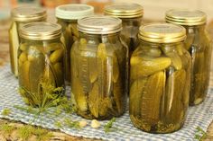 six jars filled with pickles sitting on top of a blue towel