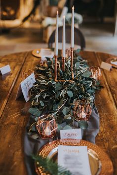 the table is set with candles and greenery for an elegant touch to the place setting