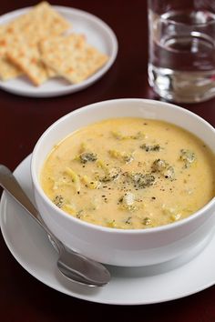 broccoli cheese soup in a bowl with crackers and water on the side