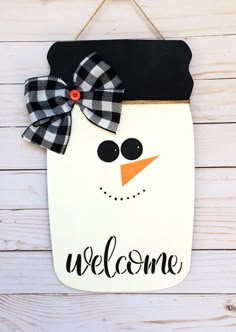 a welcome sign with a snowman wearing a black and white bow