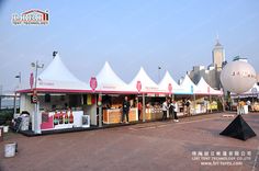 several tents set up in the middle of a brick road with people standing around them