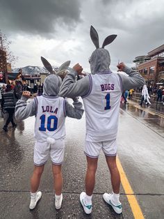 two people in bunny ears are standing on the street with their arms around each other