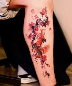 a person with a tattoo on their arm that has red flowers and black birds all over it