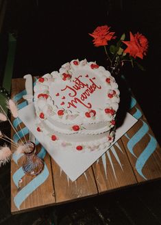 a heart shaped cake sitting on top of a wooden table next to flowers and candles