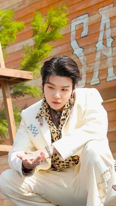 a man in white suit and leopard print shirt crouching down with his hands on his knees