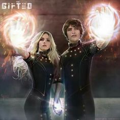 two people in black outfits holding up their hands with glowing orbs on the fingers