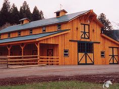 a large wooden barn sitting next to a forest