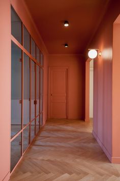 an empty hallway with pink walls and wood flooring is pictured in this image from the inside