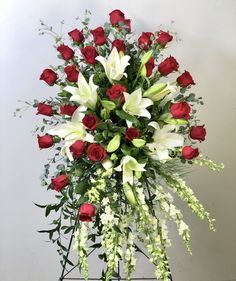 a bouquet of roses and lilies arranged on a stand with greenery in the center