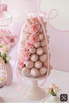 a cake with pink flowers and eggs on it sitting on a table next to other cakes