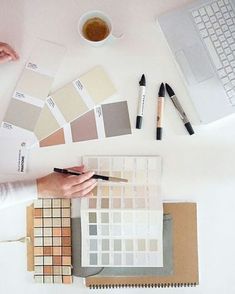 a person sitting at a desk with some paint samples on it and a laptop next to them