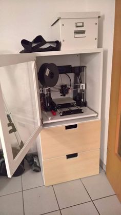 an open cabinet with a printer inside of it on top of a tiled floor next to a wall