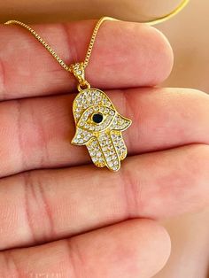 "This is a beautiful gold filled Hamsa charm necklace with evil eye center.  Hamsa Pendant is 14k gold filled, measures 23x16mm and has a blue evil eye center surrounded with clear pave crystals.  This pendant comes on a 14k gold filled box chain with spring clasp in back.  This necklace comes on a  16\", 18\" or 20\" length.  Model is wearing the 16 inch length.  Comes nicely boxed, the perfect. Why you should choose Gold Filled Jewelry... Gold filled jewelry is an actual layer of gold pressure 14k Gold Filled Evil Eye Jewelry, Gold Evil Eye Pendant Charm Necklace, 14k Gold Evil Eye Charm Necklace, 14kt Gold Jewelry, Hamsa Necklace Gold, Hamsa Evil Eye, Custom Necklaces, Eye Center, Clean Sterling Silver