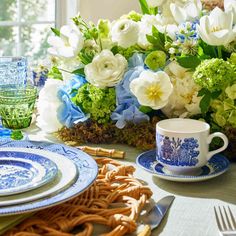 a blue and white table setting with flowers