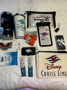 the contents of a disney cruise line bag are laid out on a bed with white sheets