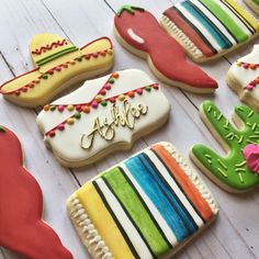 decorated cookies with different colors and designs on a white table top, including one that says fiesta