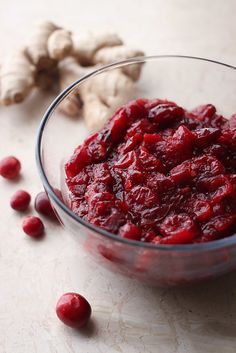 a glass bowl filled with cranberry sauce next to fresh ginger