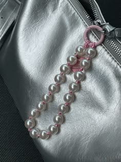 a silver purse with pink and white beads hanging from it's front pocket,