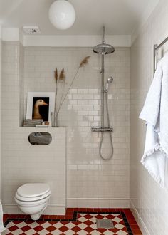 a white bathroom with red and white checkered flooring, an open shower head