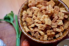 a wooden bowl filled with food next to carrots and celery sticks on a table