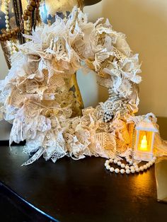 a candle is sitting on a table next to an ornate wreath and pearls necklaces