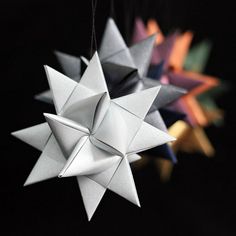 an origami star hanging from a string with other paper stars in the background