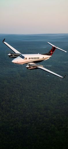 an airplane is flying in the sky over some trees