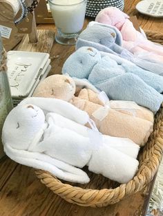 a basket filled with lots of stuffed animals on top of a wooden table next to a glass of milk