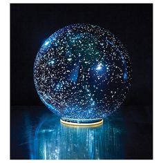 a large blue ball with stars on it sitting on a reflective surface in front of a black background