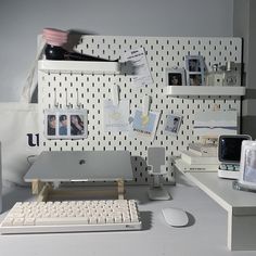 a desk with a keyboard, mouse and pictures on the wall behind it in an office