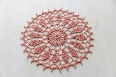 a pink crocheted doily on a white surface