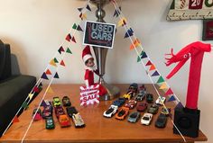 a table topped with lots of toy cars next to a sign that says used cars