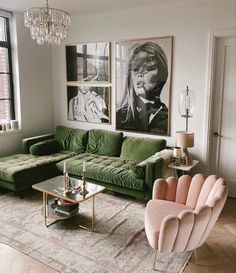 a living room with green couches and pictures on the wall above them, as well as a chandelier