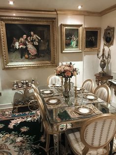 a dining room table with chairs and plates on it in front of two framed pictures