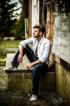 a man sitting on a bench in front of a building with his feet propped up against the wall